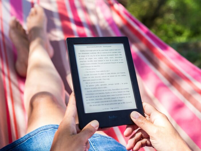 A person reading a story on an Amazon Kindle, showing how readers engage with your work as you build your readership.