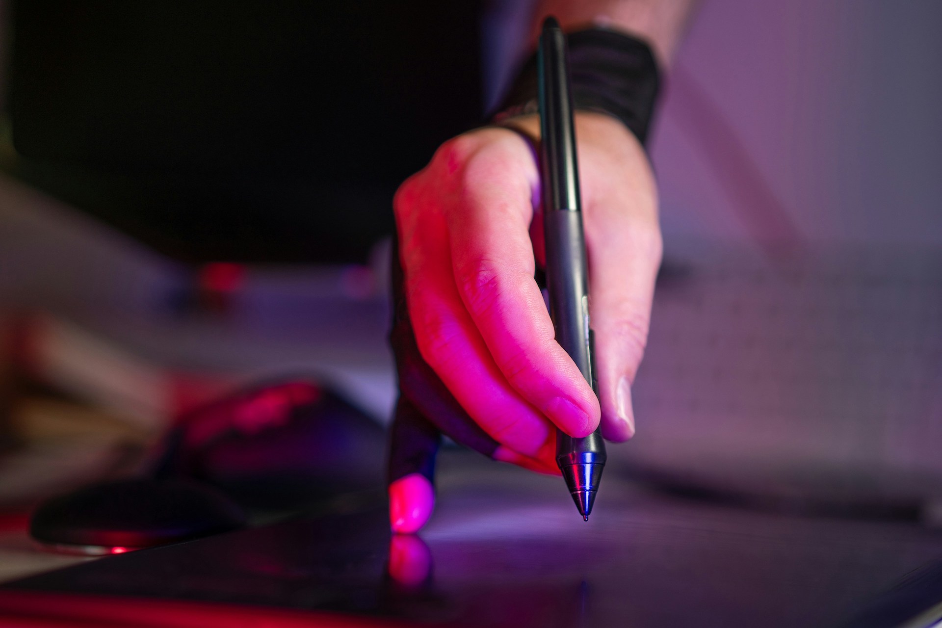 A person holding a pen and working on a laptop, creating content for an artist’s guide to selling.