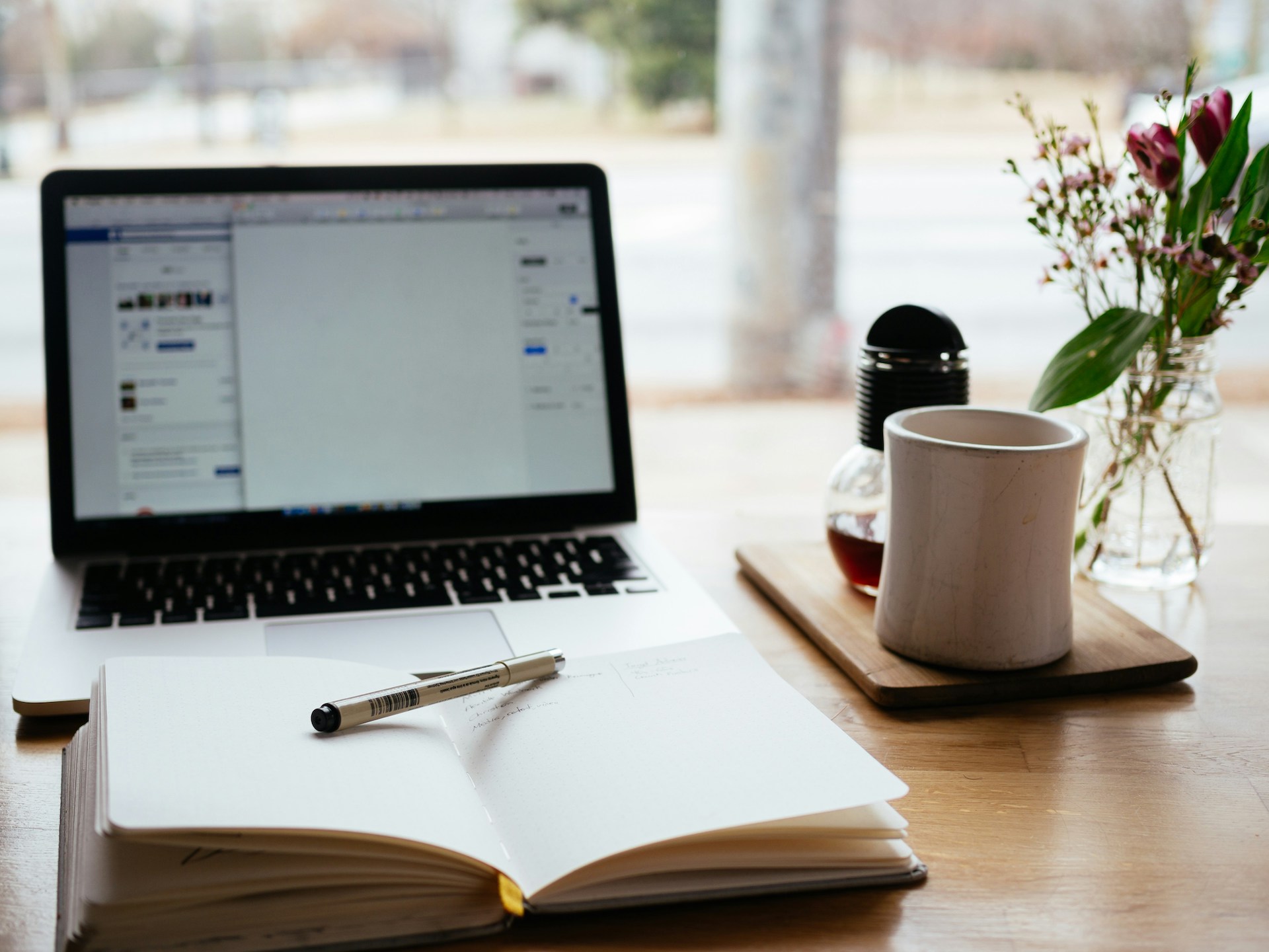 A notebook, a computer, and a mug on a desk, capturing the quiet ritual of writing morning pages to clear the mind and spark creativity.
