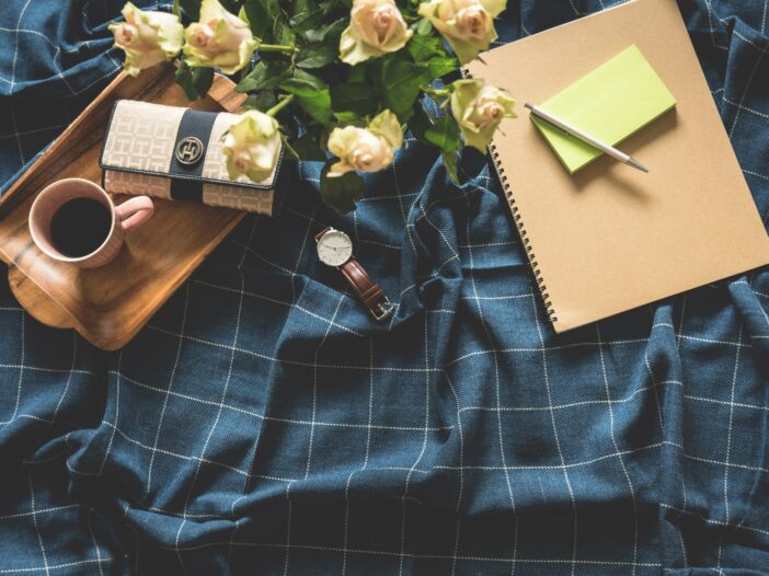A coffee cup, notebooks, and a watch at the center of a workspace, symbolizing the busy and dynamic life of a multipassionate creative.
