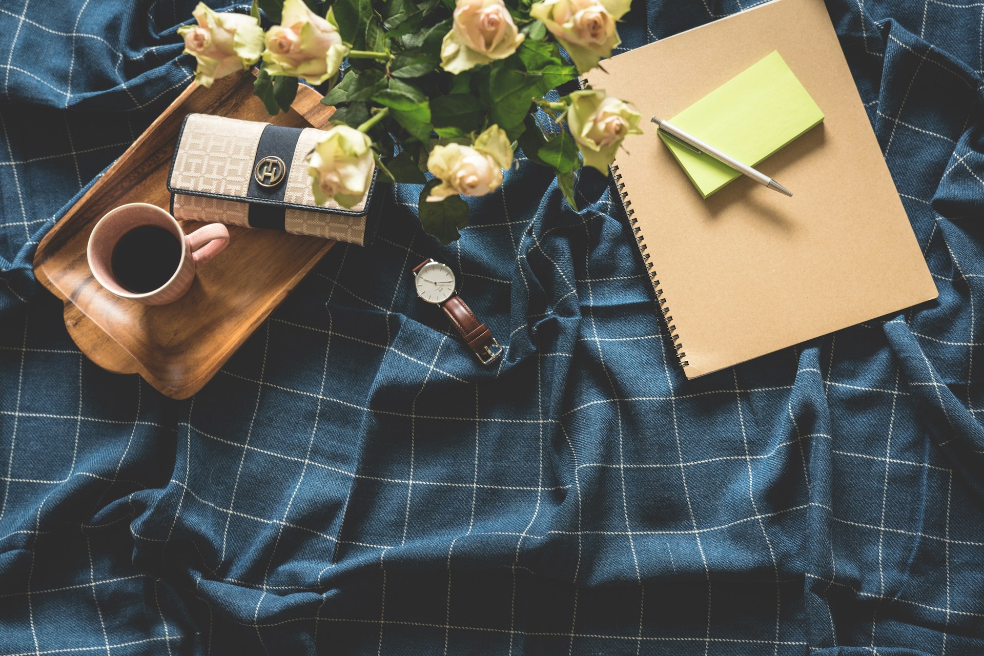 A coffee cup, notebooks, and a watch at the center of a workspace, symbolizing the busy and dynamic life of a multipassionate creative.