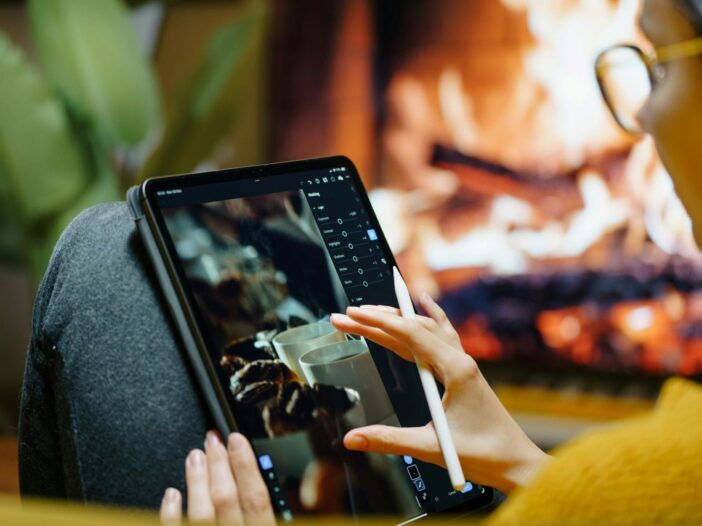Person using a tablet by the fireplace, researching freelancing for journalists.