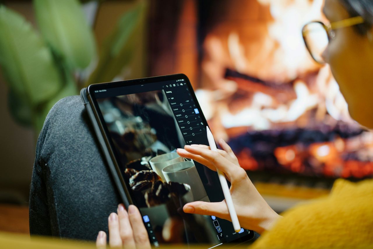 Person using a tablet by the fireplace, researching freelancing for journalists.